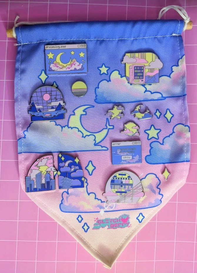 Photo of several pastel sky-themed vaporwave enamel pins on a matching fabric pennant banner.  Behind the banner is a pink grid pattern.