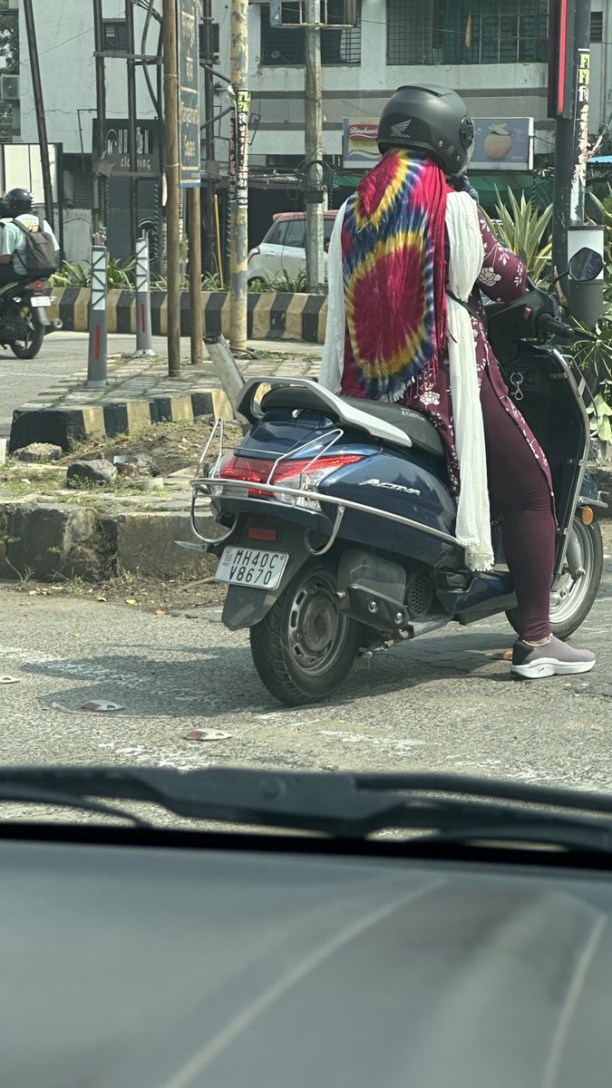 This lady driving two wheeler without rules if the road in middle of the road.