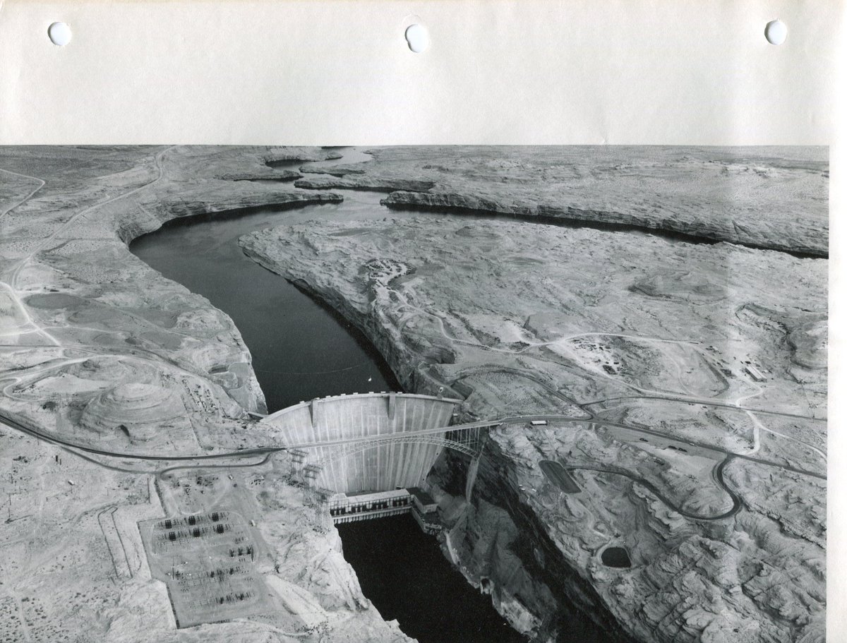 Aerial view of Glen Canyon Dam and Lake Powell near full pool Horizontal black and white photograph. The original, which is stored in Museum Archives, has three ring punches on top of photo and slight warping; USBR info on back.

Dates: 1965