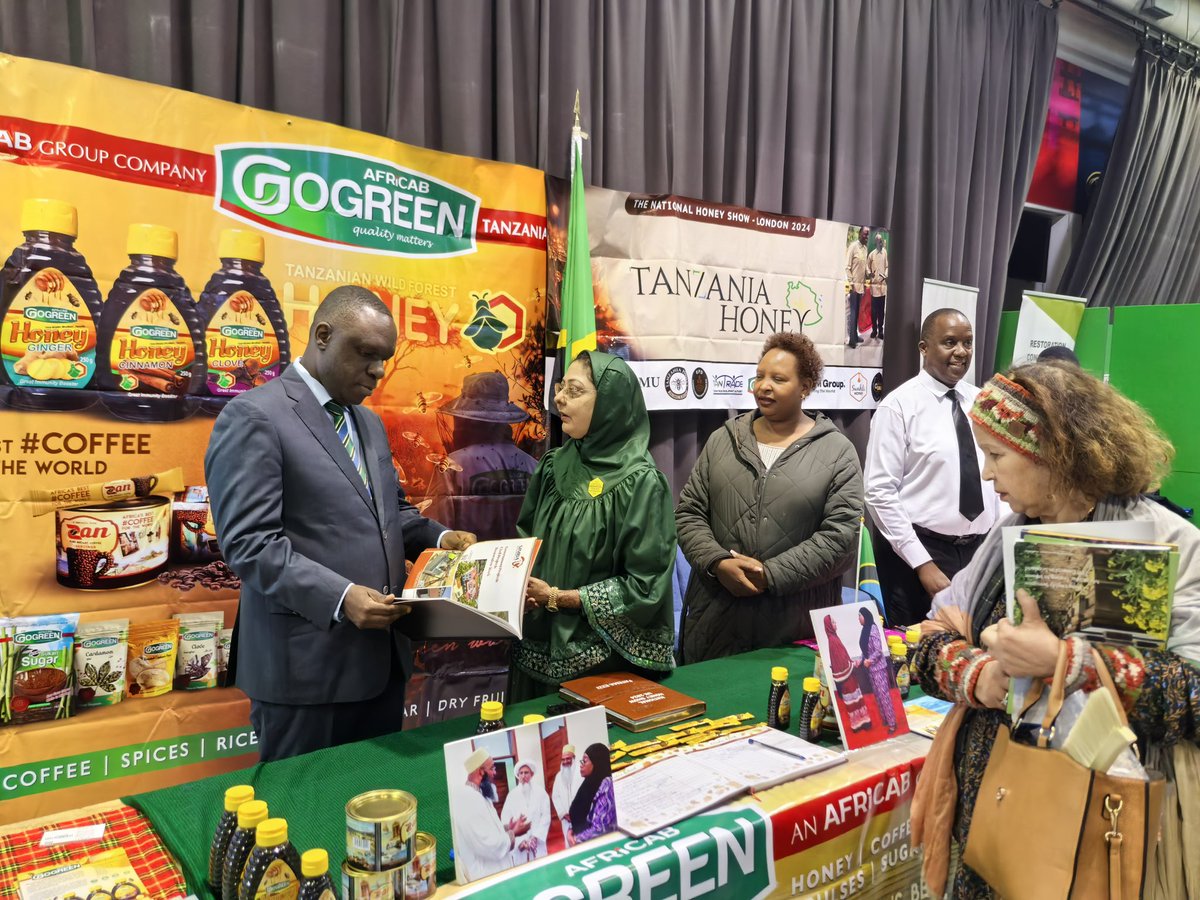 UbaloziUK's tweet photo. Asali ya Tanzania - Swahili honey, Go Green honey,  na Miombo yawa kivutio katika maonesho ya Asali yaliyoanza jana jijini London.  Imeelezwa kwamba kuanzia mwezi January 2025 asali hiyo itaanza kuuzwa katika maduka makubwa nchini Uingereza. Balozi @MbelwaK ametembelea maoenesho hayo leo na kutoa pongezi kwa Makampuni ya PMM, African Group, Central Park Bees na FREMU kwa kuchangamkia soko la Uingereza na amewaahidi ushirikiano wa Ubalozi katika kutafuta masoko mapya