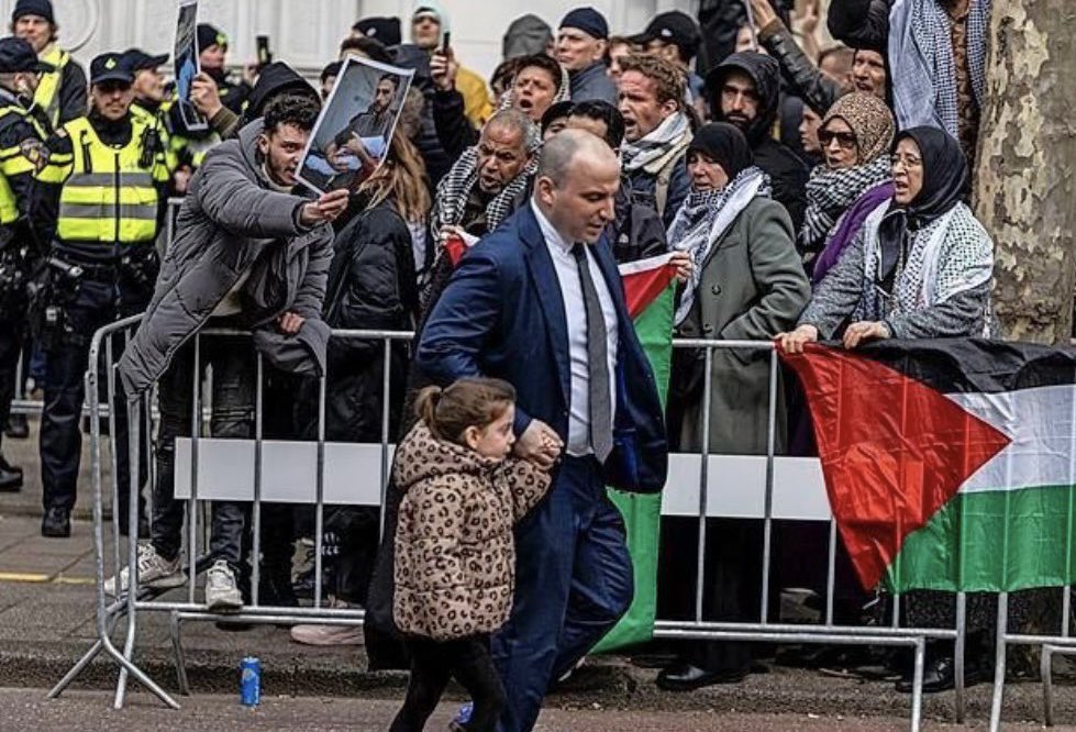 RachelMoiselle's tweet photo. Look at this photo. This is of the opening of a Holocaust museum in Amsterdam in March. 

The child is the great-granddaughter of one of the very few Amsterdam Shoah survivors: Rudie Cortissos. 

As you can see, they were abused entering the museum. Heartbreaking videos are in the public domain of Rudie placing a mezuzah on the door of the museum to the sounds of antisemitic chants in the background. 

This too was dismissed and rationalised. Why? Because Isaac Herzog was in attendance. 

There will always be a reason to justify hatred against Jews. It will always be positioned as somehow deserved. Always.
