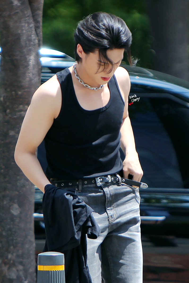 wooyoung looking down, wearing a black tank and jeans