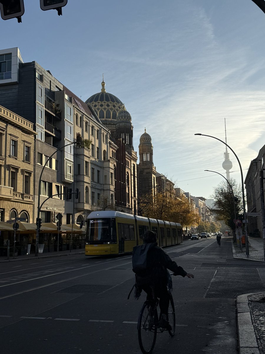 echoesofberlin's tweet photo. Morning in Berlin: A cyclist passes the iconic New Synagogue with the TV Tower in the distance, as a yellow tram glides down the quiet street.

#Berlin #Cityscape #MorningVibes #UrbanLife #Cycling #BerlinArchitecture #StreetPhotography https://t.co/BK20DEIWBo