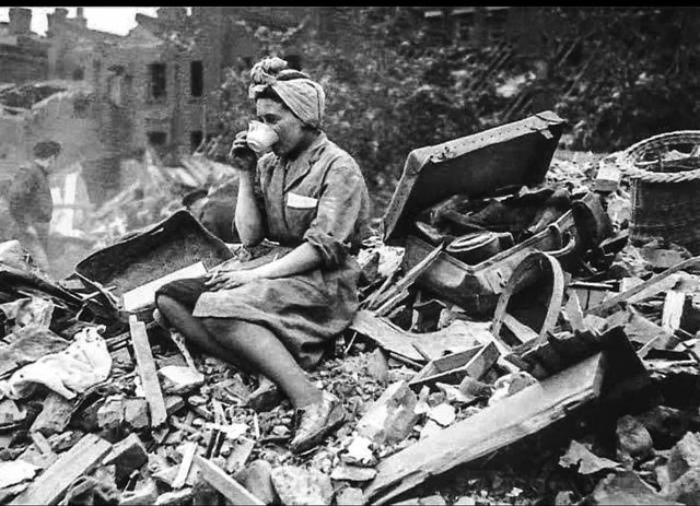 A woman sitting with a cup of tea in the ruins of her house after the heavy bombing of London, 1940.