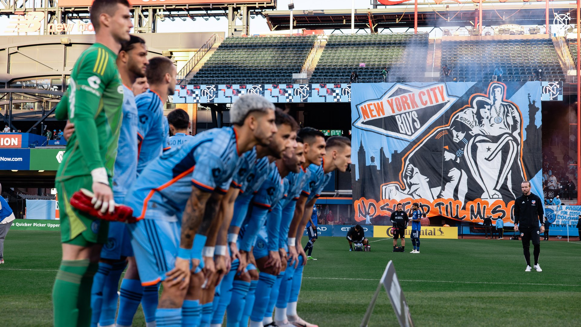 The team photo with the Tifo in the background. 