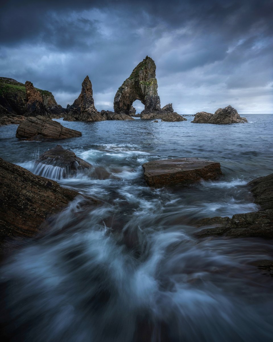 Waves crashing against the rugged shore in front of the Crohy Head Sea Arch in Ireland 🇮🇪