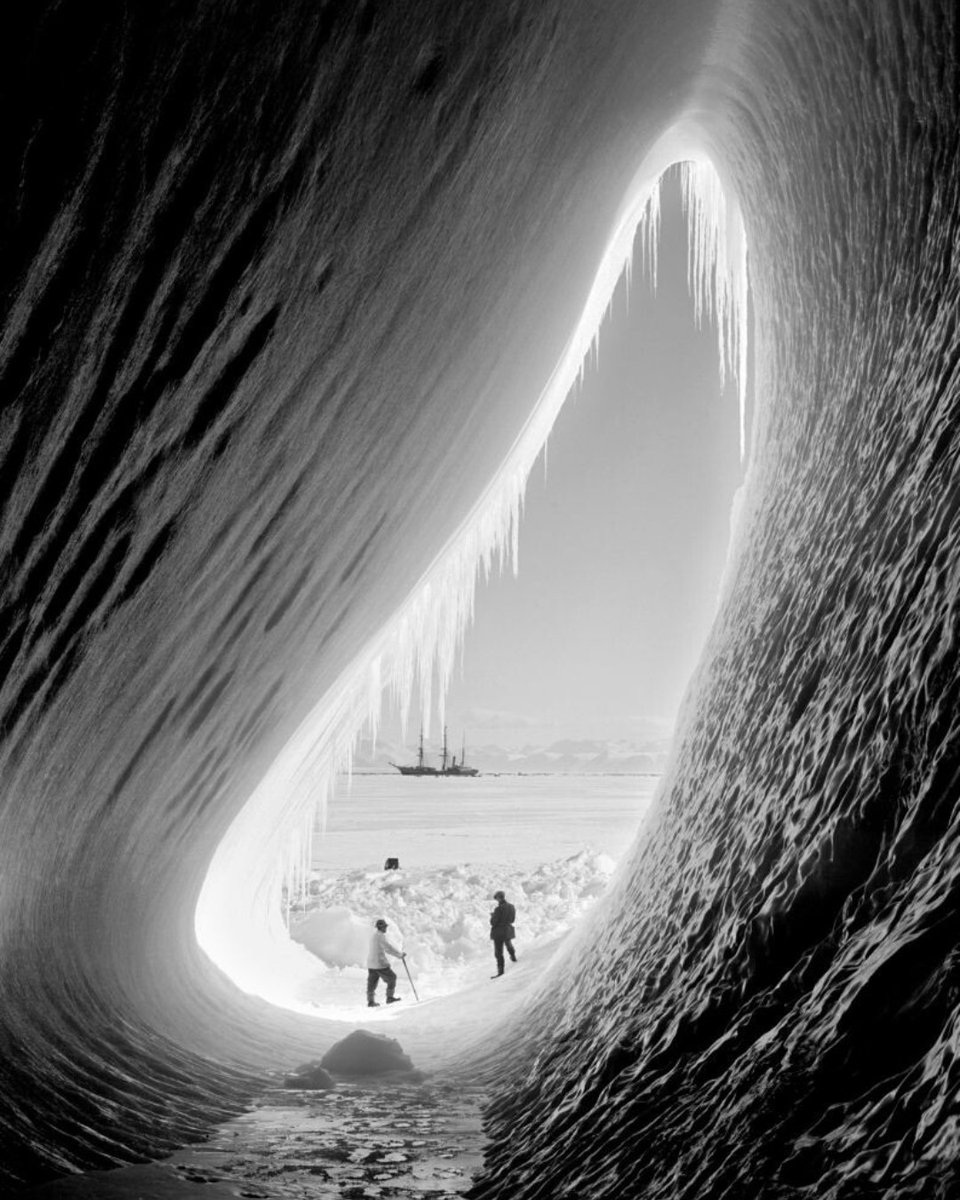 This photograph was taken in 1911, in Antartica. The Terra Nova – the supply ship for Robert Falcon Scott’s second Antarctic expedition – can be seen in the distance while two of the crew explore an ice grotto. 

📸 Getty