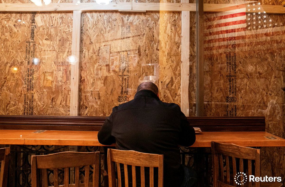 A person eats inside of a restaurant with plywood covering the windows near the White House in  Washington, U.S., November 4, 2024. REUTERS/Nathan Howard