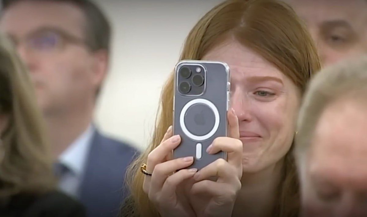 Жена Эрнеста с первого говноканала снимает на IPhone речь мужа, в которой он сравнивает Стива Джобса с Гитлером, за то что Джобс придумал IPhone