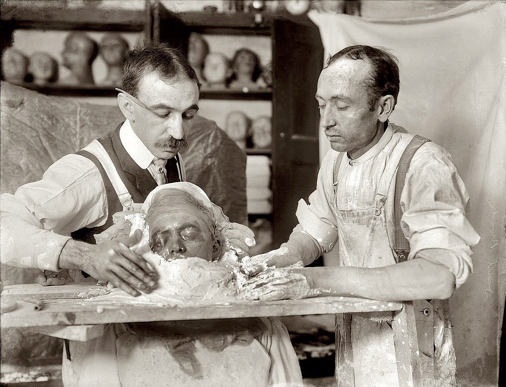 PastMedHistory's tweet image. Two men in the process of making a death mask, New York, c. 1908. A death mask is a likeness of a person's face after their death, usually made by taking a cast from the corpse. They were often used as mementos of the dead or for the creation of portraits. #histmed #deathmask
