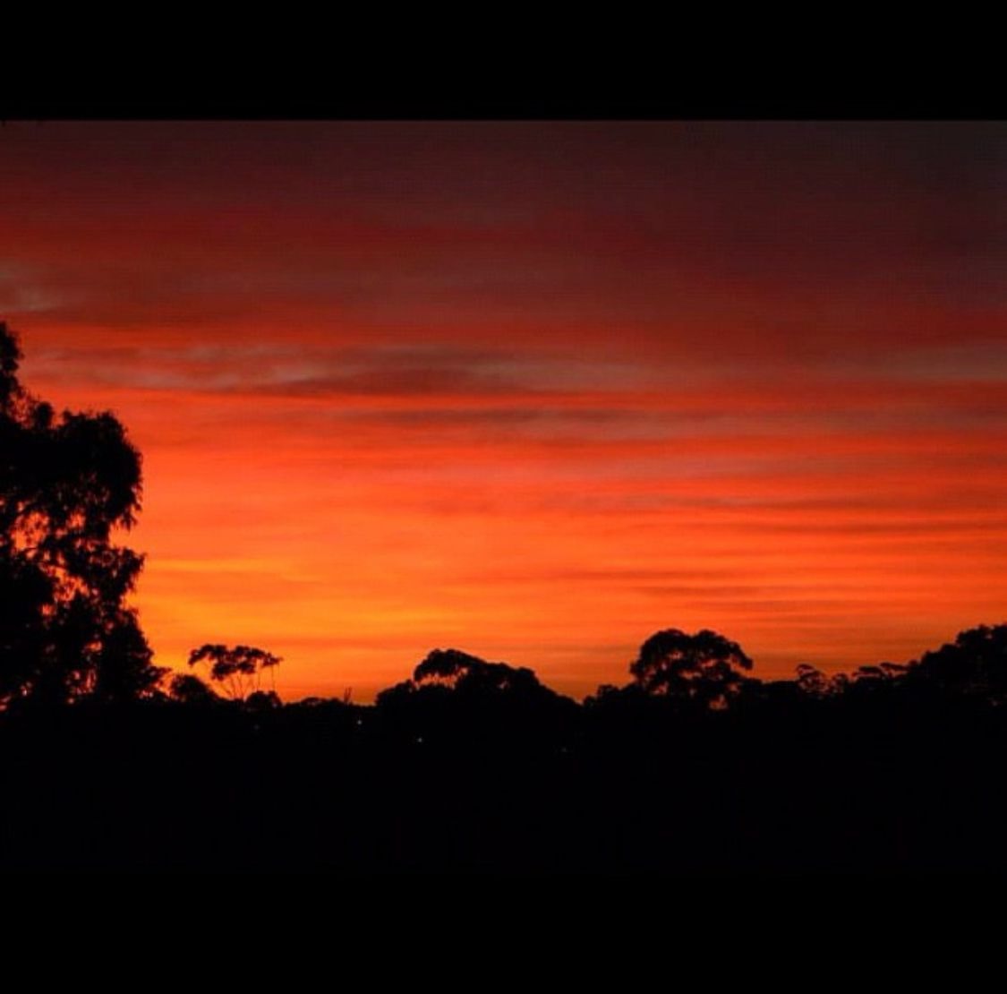The sun sinks slowly, leaving behind a trail of fiery colors that fade into the cool blues of evening.