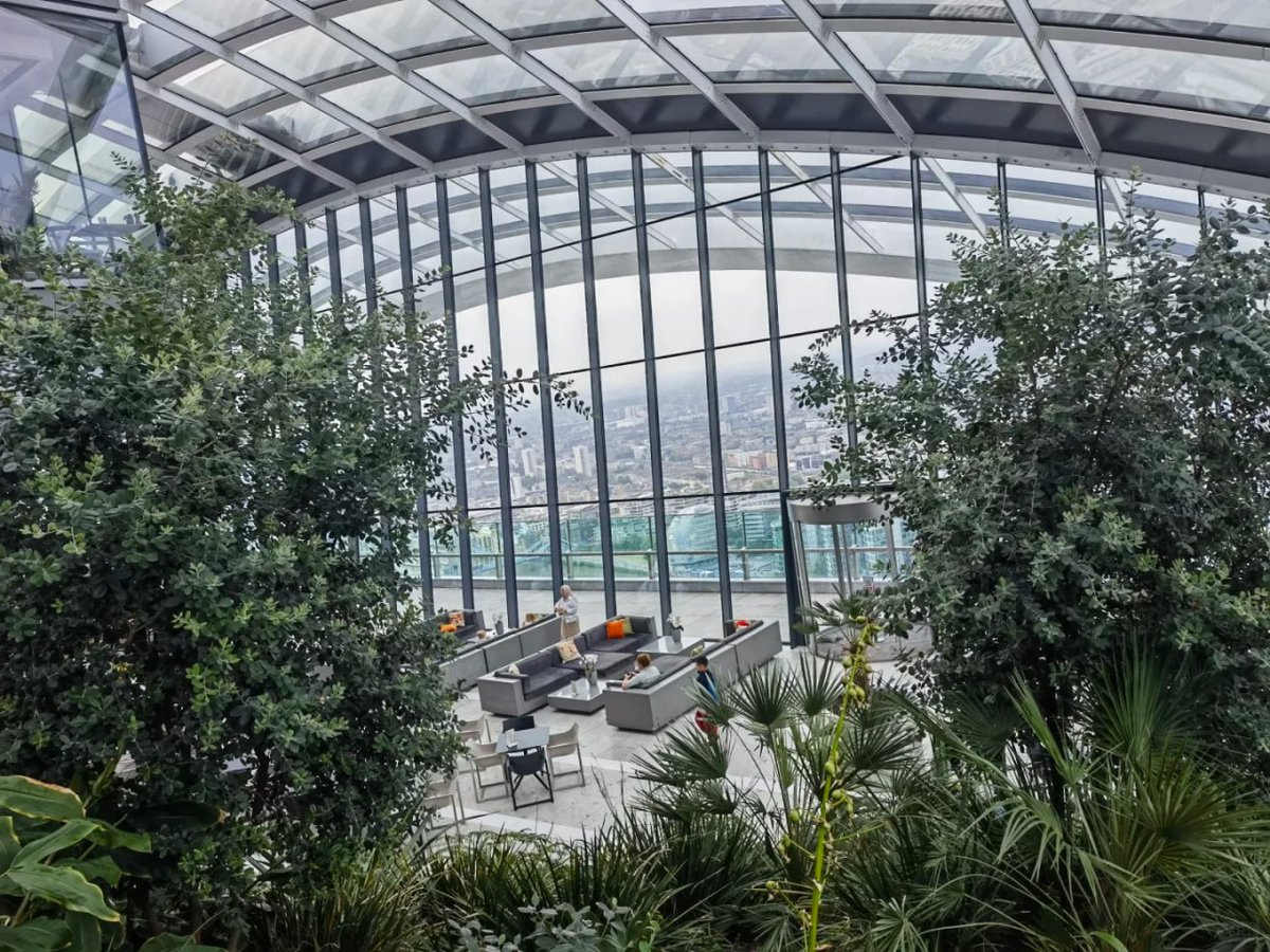 orientalli's tweet image. The interior of the Sky Garden featuring seating areas, visitors, and a view of the skyline through large glass panels.