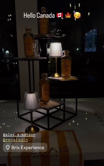 Bottles of gin displayed on a tiered stand with small lamps, labeled 'Hello Canada.'