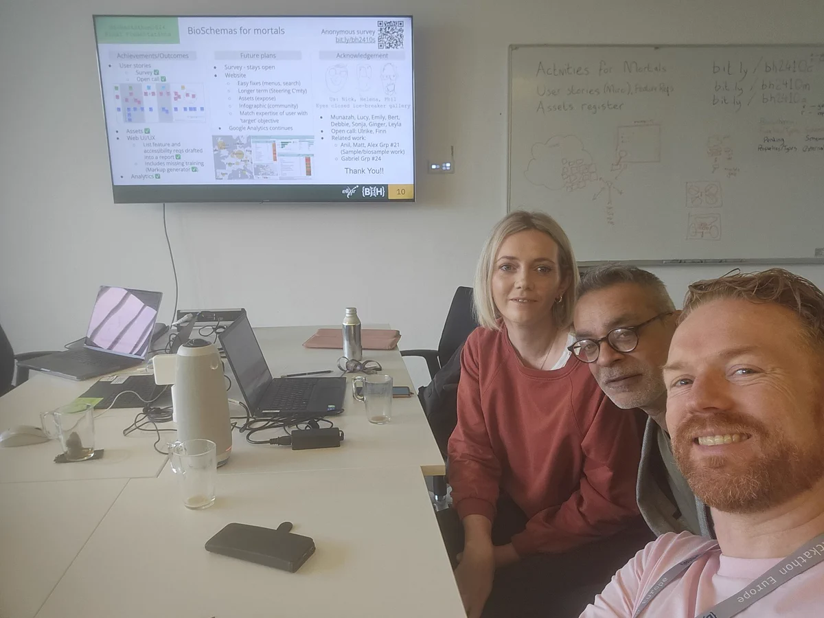 Three people in front of a TV screen showing a presentation slide