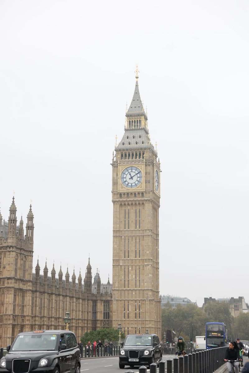 Big Ben and the Houses of Parliament towering over the Thames with boats on the river