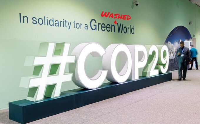 Photo of the entrance of COP29, where a poster reads: in solidarity for a Green World #COP29, and the word Washed was hand written after the word Gree, reading then: in solidarity for a Green Washed World #COP29