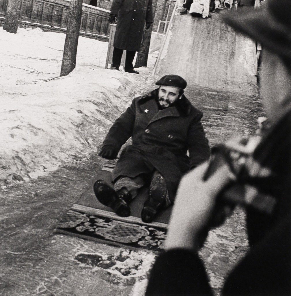 Fidel Castro slides down an ice slide on a rug, USSR, January 1964