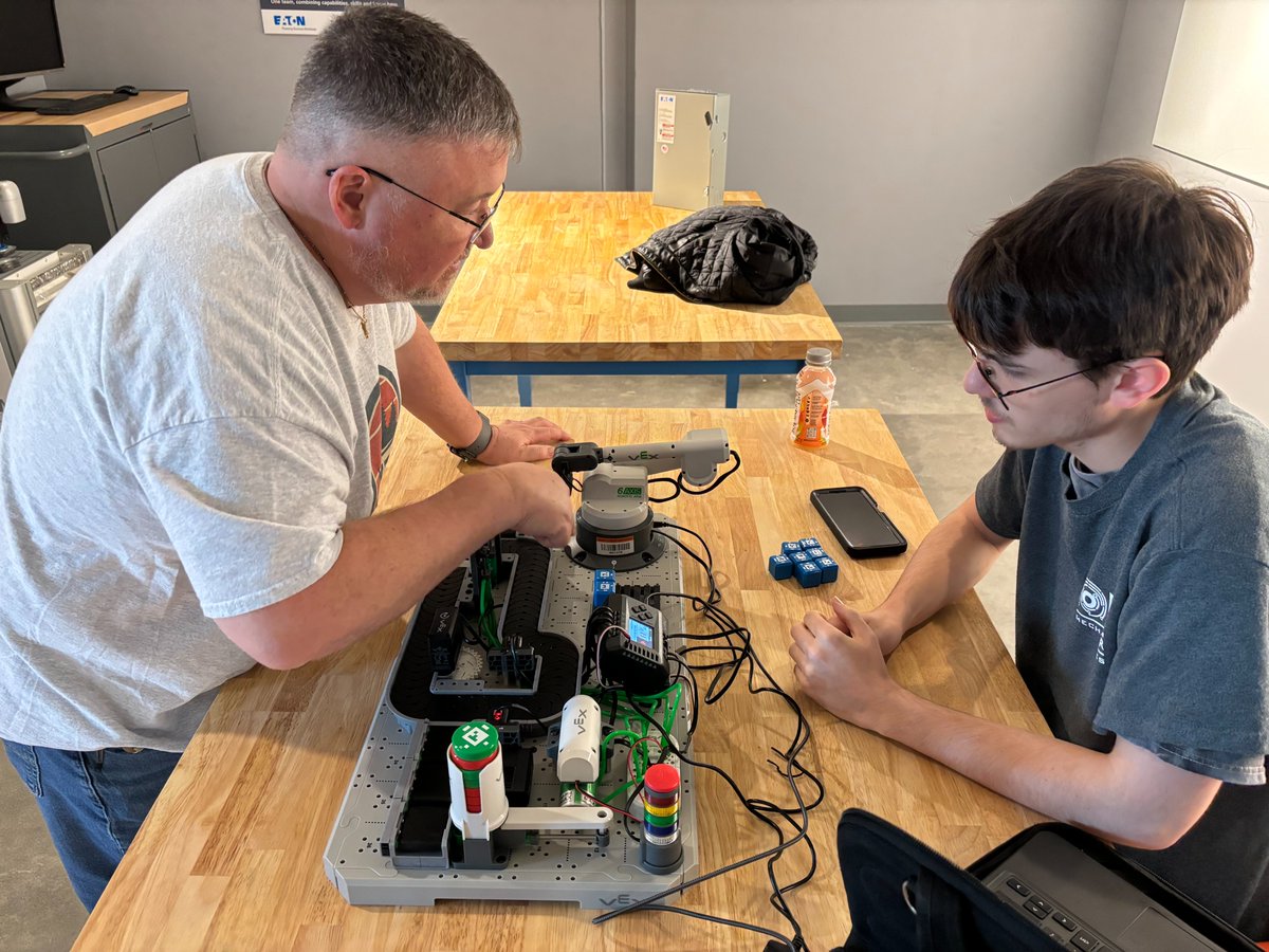 TechnologyBCS's tweet image. BCHS Senior, Denny Gardner and @PIE_Center_BCS Mechatronics teacher Dak Keylon work to create an automated sorting program on a VEX CTE Workcell, as a part of the Motor Controls and Practicum classes. This equipment is on loan from the new BCS STEM Hub lending library. #STEMHub