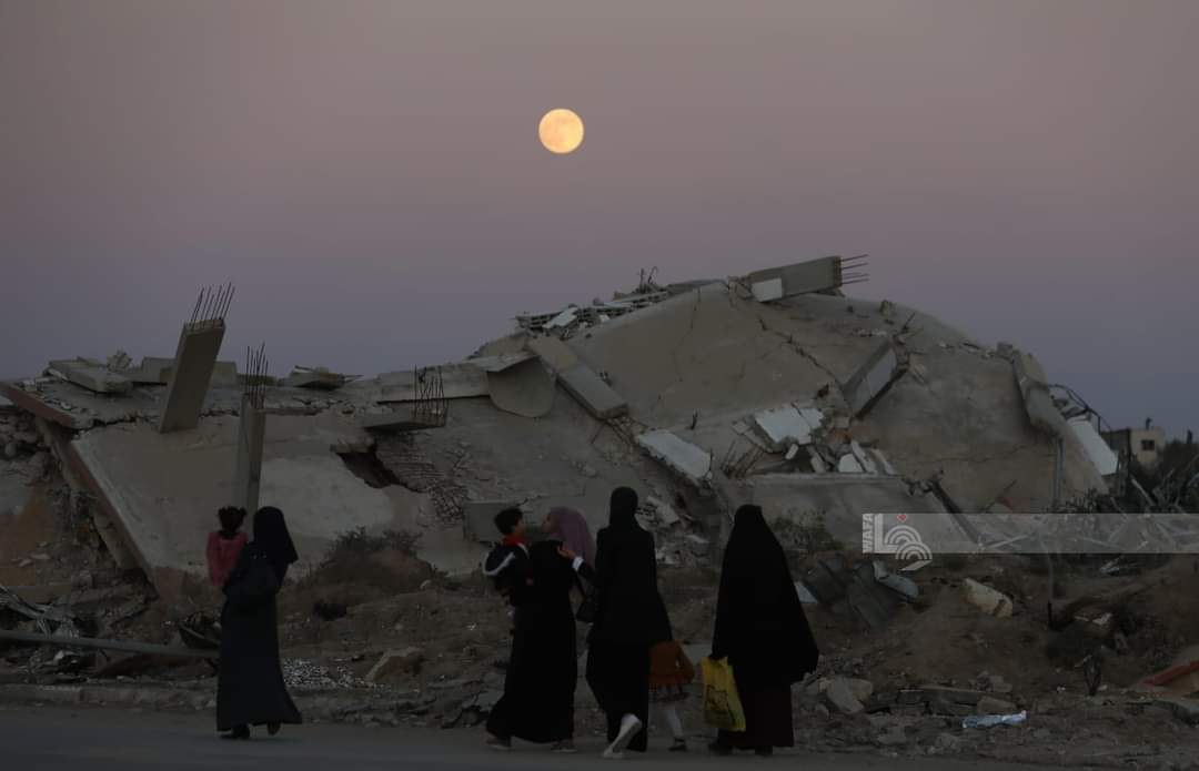 WAFANewsEnglish's tweet photo. Locals pose for pictures with the full moon  above the destroyed buildings in the town of Zawayda, central Gaza. https://t.co/QmizytsH4m