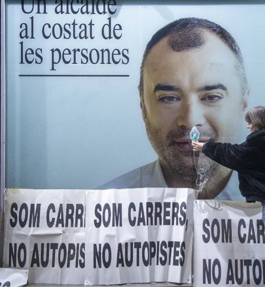 Protesta en #Terrassa contra la contaminación y contra una ciudad al servicio de los coches, 17.000 al día pasan por dos calles del centro, Arquímedes y Galileu.
Una vecina le pone una mascara de respirador al alcalde, fotaza de <a href="/AlbertoTallon/">Alberto Tallón 🏴‍☠️</a> 
¡La revolución verde era un cuento!