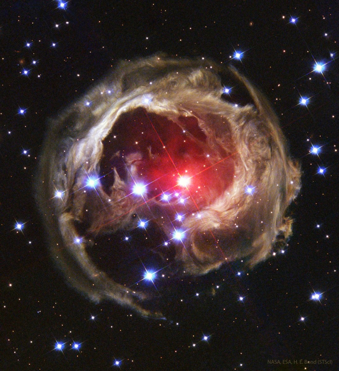 alex_riveiro's tweet photo. Este curioso paisaje es V838 Mon (o Monocerotis), a principios de 2002. En aquel entonces, la superficie de la estrella se expandió enormemente, convirtiéndose en una de las estrellas más brillantes de la galaxia. Lo que vemos, es el reflejo de la luz de la estrella en el material en su entorno, algo conocido como un eco de luz. La región vista aquí mide unos seis años-luz. #FelizDomingo