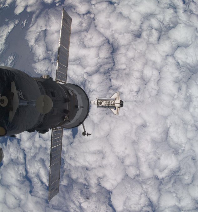 Backdropped by a blanket of clouds, Space Shuttle Atlantis is featured in this image photographed by an Expedition 21 crew member as the shuttle approaches the International Space Station during STS-129 rendezvous and docking operations. Docking occurred at 10:51 a.m. (CST) on Nov. 18, 2009. A Russian spacecraft docked to the station is at left. Credit: NASA