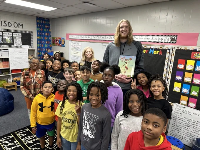 a 4th grade class stands with a 7 foot tall razorback basketball player