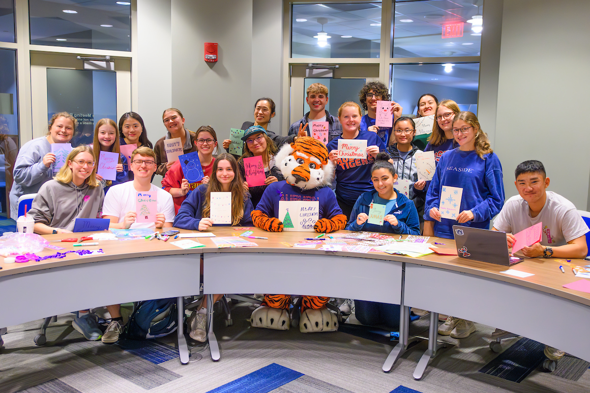 AuburnU's tweet photo. Spreading holiday cheer the #Auburn way🧡 

Aubie and students came together to create heartfelt holiday cards for local assisted-living facilities. It's the little things that make the season bright. #WarEagle https://t.co/WDsRMmtJRw