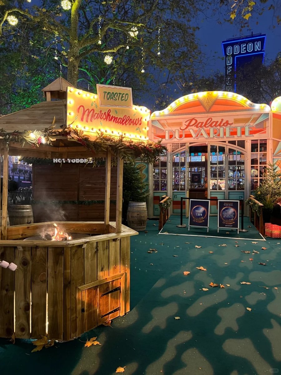 orientalli's tweet image. Crowds gather around a charming holiday stall adorned with garlands and lights, with people enjoying the lively and festive atmosphere.