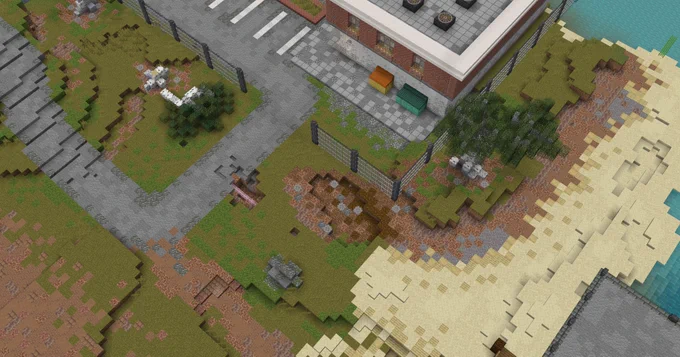 A screenshot of Minecraft depicting a dilapidated, fenced off brick building with a parking lot and two dumpsters outside. the road that leads to it has visible decay, exposing underground piping.