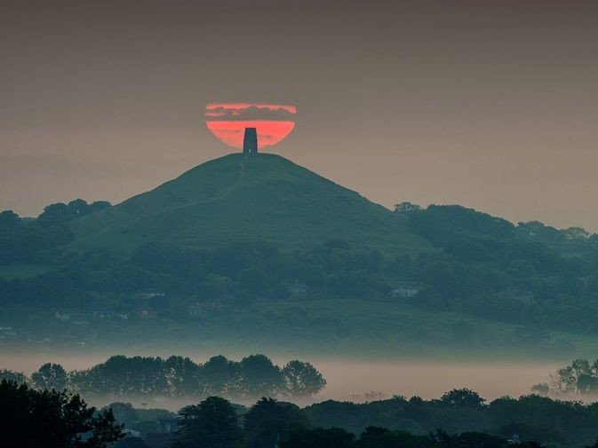 I sometimes imagine Glastonbury, in the wild west of England, as a cosmic nexus, a mystical battleground where the very fabric of reality is stretched and twisted by the hands of time-traveling sorcerers and psychedelic dreamers. The Tor stands as a towering monolith, an ancient