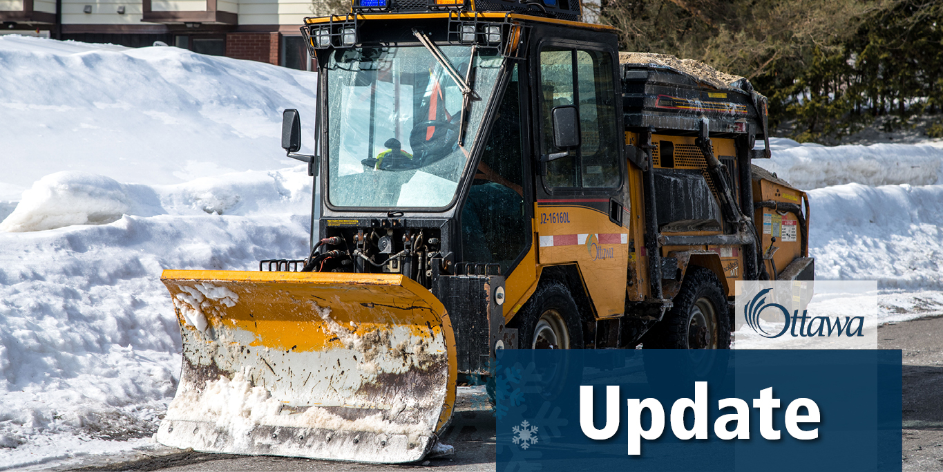 A City of Ottawa sidewalk plow with sand in the back is driving down the side of the road. A blue text box is in the bottom righthand corner with white text that reads \