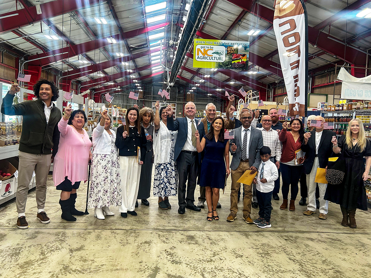USCIS's tweet photo. This year we are thankful for these 18 #HurricaneHelene survivors who became #NewUSCitizens at the Asheville, N.C. farmer’s market. USCIS Charlotte staff went to the mountain city ravaged by the storm to facilitate their naturalization and administer the Oath of Allegiance. https://t.co/QgscftNMi1