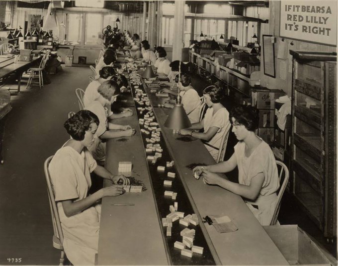 Women on an assembly line (sitting) and putting bottles of insulin in packages