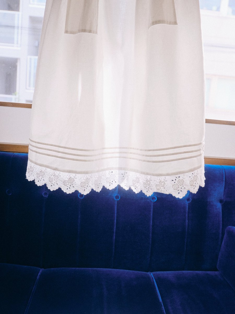 エプロンの裾を飾る幅広のコットンレースは喫茶閃光のショップカードや