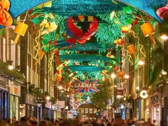 orientalli's tweet image. A vibrant carnival of colors and lights illuminates the lively street, filled with festive energy."