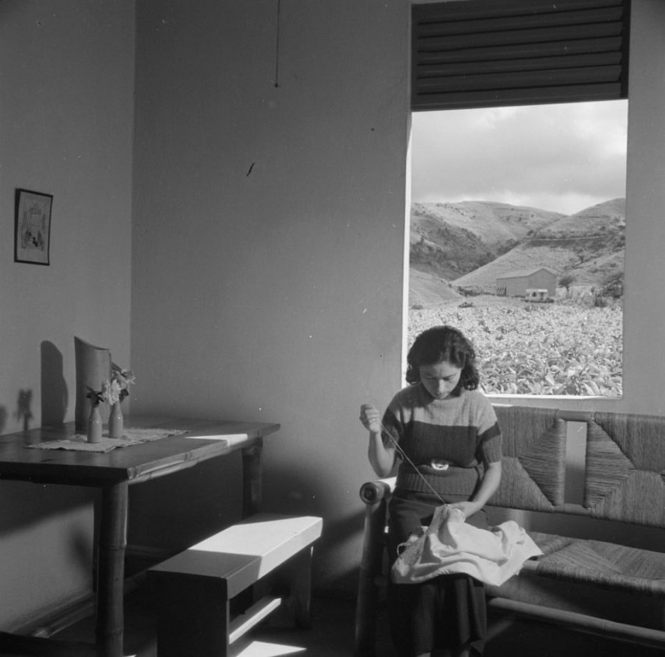 Foto de una mujer cosiendo en su residencia en Aibonito. Aibonito, Puerto Rico. 1938