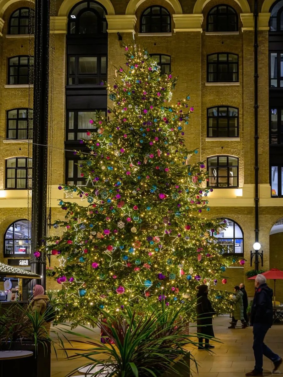 orientalli's tweet image. The illuminated Christmas tree, beautifully decorated with stars and ornaments, brightens up a busy indoor area.