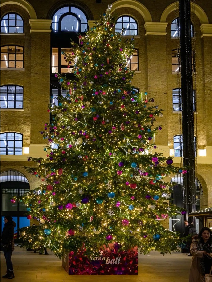 orientalli's tweet image. The illuminated Christmas tree, beautifully decorated with stars and ornaments, brightens up a busy indoor area.