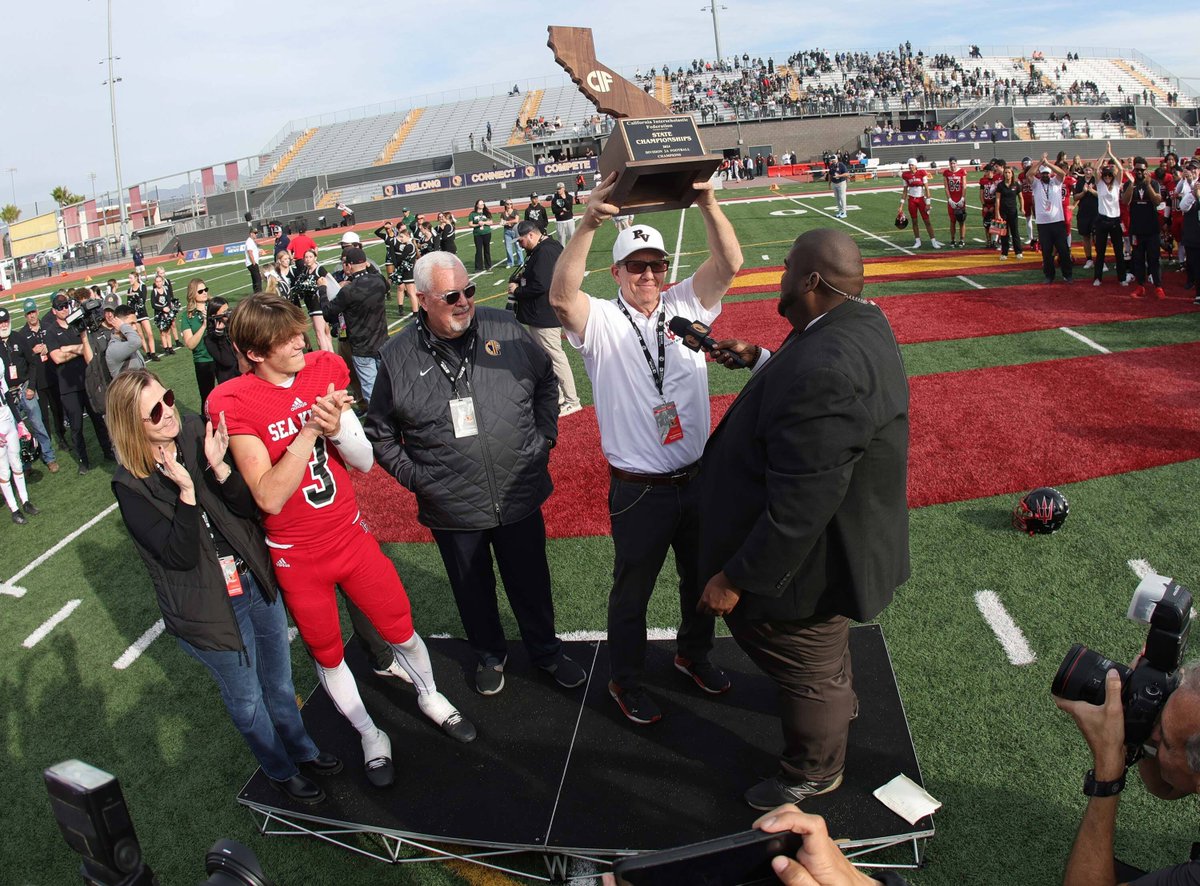 Palos Verdes coach Guy Gardner lifts the CIF State trophy as his sophomore QB Ryan Rakowski looks on.

Photo by Todd Shurtleff