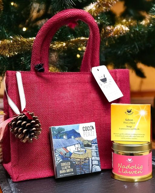 🎁 Christmas Gift Bag 🎁

A festive red hessian bag filled with:
✨ Nadolig Llawen Candle
🍫 Coco Pzazz Chocolate
🧼 Frankincense &amp; Myrrh Soap
🌲 Pine Cone Tree Decoration
Spread Welsh charm &amp; holiday cheer! 🎅🎉
👉 myddfai.com
#NadoligLlawen #ChristmasGifts
