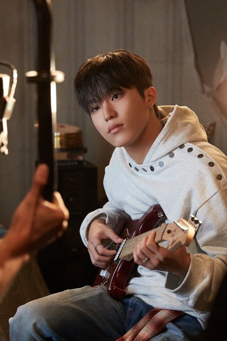 Lost in the melodic whispers of the strings, where every chord strummed becomes a window to the soul. The soft hoodie and relaxed denim give off an effortless charm, making this a portrait of creativity at its most authentic.