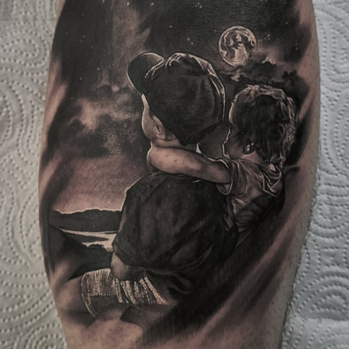 JayTAT2's tweet photo. A few months back, Cian sent me a photo that he loves of his kids. He asked me if i could come up with a design, using that image, but where they were sat in front of a night sky with a shooting star instead of the original background of the photo. 
Today, Cian flew over from Ireland for his appointment. 
He and I are both made up with how this turned out.

Thanks to all my clients who come from far and wide to get tattooed by me. I love this job and appreciate you all ❤️

Swipe to see the original photo

Tattoo Appointments email - jay.hutton@outlook.com