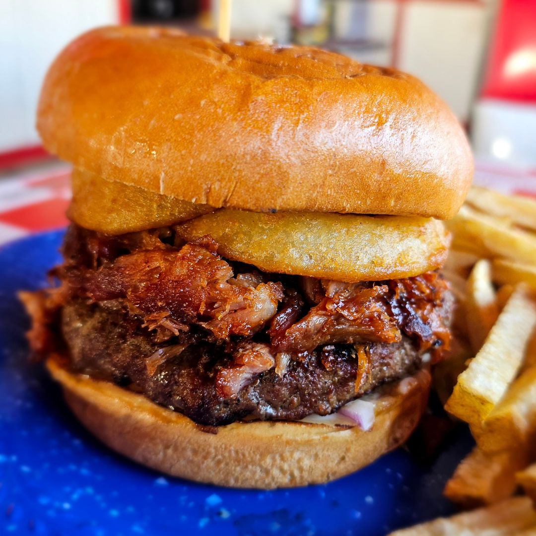 Introducing our December #BurgerOfTheMonth: the #BBQPulledPorkBurger! 🍔

🍔🔥 A  1/2lb charbroiled burger, smothered with 1/2lb of smoky pulled pork, drizzled in BBQ sauce, and topped with crispy onion rings!

 #MeatLovers #VisitTemecula #OldTownTemecula