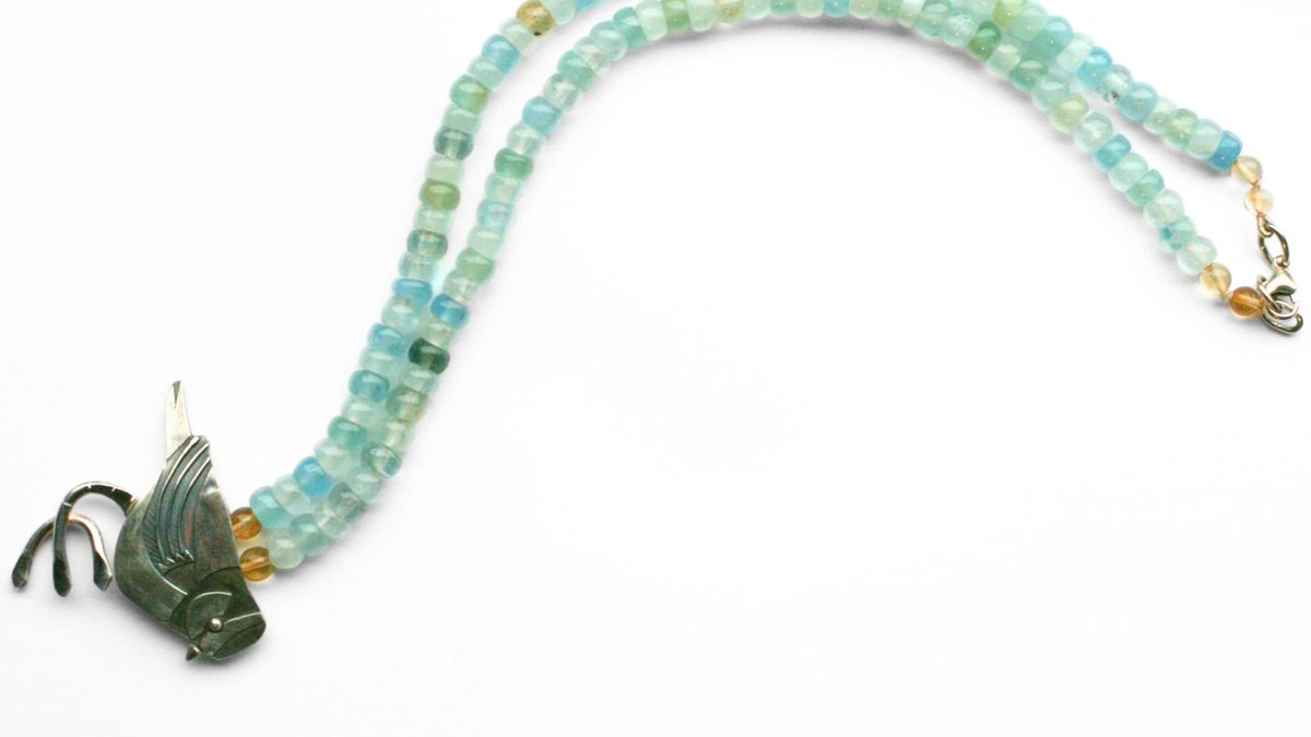 This pendant by Anna de Ville features a lively blue tit, crafted by layering multiple oxidised silver components and wires to achieve both detail and depth. The aquamarine, green, yellow and blue hues of the beads thoughtfully replicate the tit's characteristic plumage.
