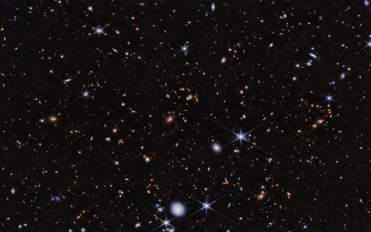 Im Schwarz des Alls unzählige leuchtende Punkte, darunter über 100 extrem weit entfernte Galaxien. Außerdem einige nahegelegene Sterne, die sich an ihrer Helligkeit und den sie umgebenden Strahlen verraten. Diese Strahlen sind Artefakte, also am Teleskop entstandene optische Effekte.