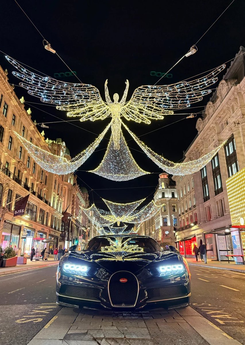 orientalli's tweet image. A night scene featuring a luxurious car underneath stunning street lights shaped like angels, enhancing the festive atmosphere.