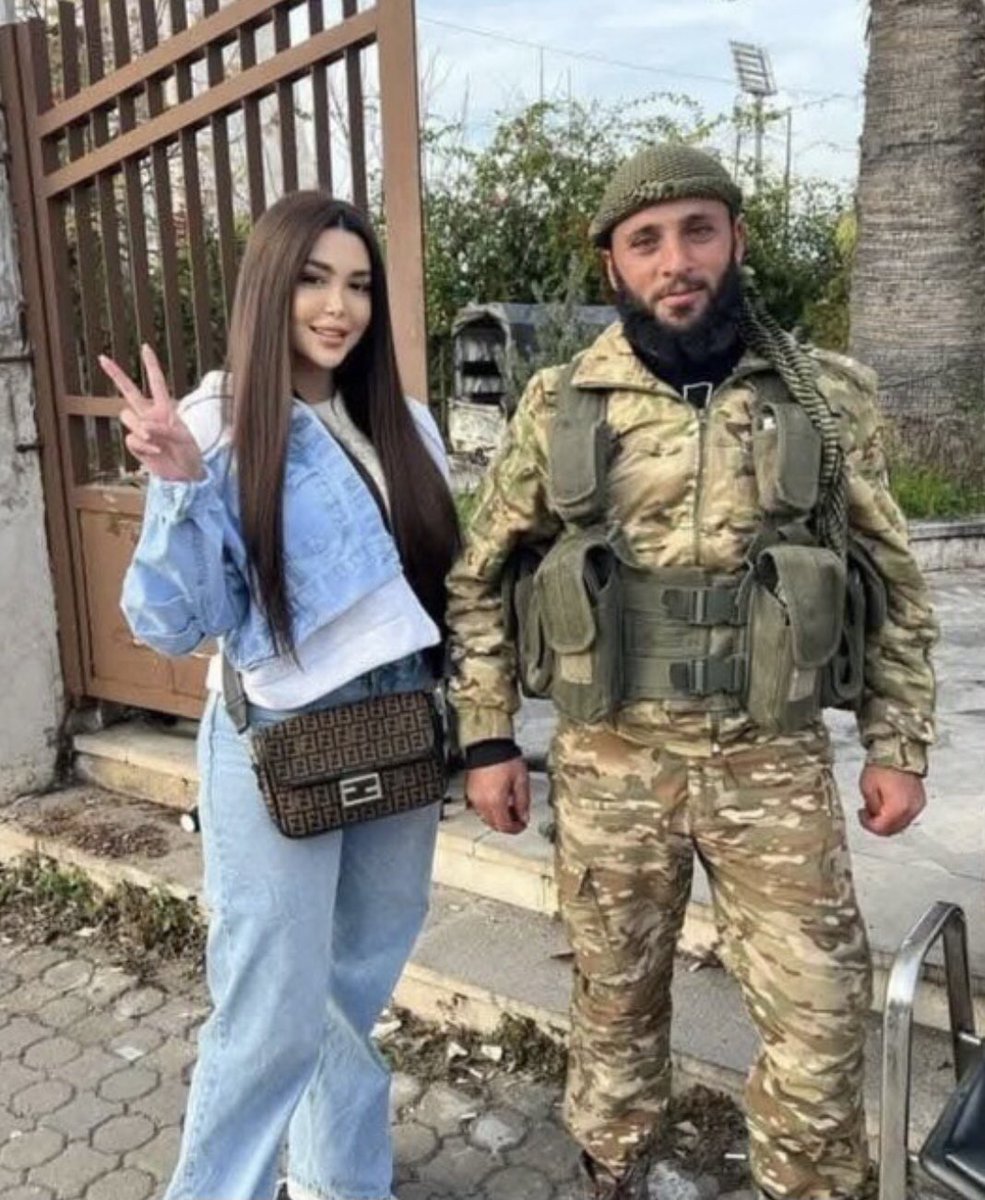 HTŞ askeriyle hatıra fotoğrafı çektiren , Suriyeli bir Kız , oysa başı açık olduğu için bir ay sonra kırbaçlanacak .