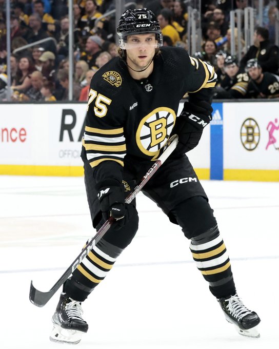 Alec Regula skates in a black Bruins jersey during a Boston home game