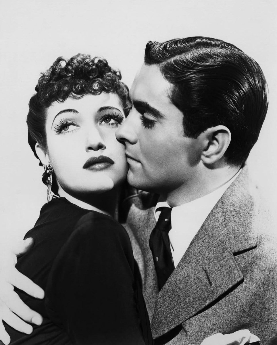 JuanmadelaPoza's tweet photo. #TyronePower y #DorothyLamour en una fotografía publicitaria de #JohnnyApollo (1940), del gran #HenryHathaway. Obra maestra prácticamente desconocida que deberías ver para comprobar la solidez de la industria cinematográfica estadounidense en esos años, cuando el #CineClásico de #Hollywood se encontraba en todo su esplendor. ¿Por qué casi no nadie la conoce y ni siquiera se llegó a estrenar en España? Misterios del #Cine. Me fascinan estas obras maestras desconocidas, esas películas que no suelen verse casi en ningún sitio, están escondidas, agazapadas en algún rincón. Ese cine clásico que destila buen gusto, esos guiones maravillosos, esos actores que llenan la pantalla, esas bandas sonoras inolvidables, esas grandiosas fotografías en blanco y negro. Un gran director siempre saca lo mejor de sus actores y eso es lo hace Henry Hathaway con un reparto impresionante. A la cabeza, uno de sus actores favoritos, un joven Tyrone Power, que aprovecha las posibilidades enormes de su personaje para deleitar a los espectadores con una interpretación espléndida (la escena del ojo morado y el filete de carne cruda resulta inolvidable). El papel del protagonista está hecho a la medida de Tyrone Power. Un actor que tiene una filmografía muy interesante, seguramente menos valorado de lo que merece, muy a reivindicar. #LloydNolan pocas veces lució más su indiscutible talento, al igual que #EdwardArnold (aunque esté metido en uno de sus habituales papeles). Todos los actores de reparto están fantásticos. Sin embargo, lo que más me ha llamado siempre la atención de esta película ha sido la protagonista femenina. Para mí, Dorothy Lamour era mucho más que una larga melena morena envuelta en vistosas telas de la Polinesia de Hollywood, con un ibiscum en el pelo. La actriz está fabulosa, con unos matices, una contención y una ternura admirables, sin olvidar su profunda voz sentimental. Su interpretación de la canción «It´s the begin of the end» me parece un regalo para los oídos de todos a los que nos gusta la buena música. En definitiva, en «Johnny Apollo» hay acción sin parar, amor desinteresado en los cuatro personajes principales: padre, hijo, abogado y chica, una buena fotografía y una banda sonora perfecta. Todo funciona perfectamente en esta joya del cine negro. Historia clásica de venganza y redención, de huida hacia delante, de encuentros, de amistad y decepción, y también de lucha, familia y valores. La sinopsis del filme es muy interesante: Bob Cain es alumno de universidad elitista, cuyas facturas abona puntualmente su padre, un corredor de bolsa en Wall Street. Al chico se le hunde el mundo cuando su progenitor acaba en la cárcel con una condena de muchos años por sus chanchullos en el mundo de las finanzas. Recién licenciado en la universidad, intenta conseguir trabajo para pagar la fianza. Sin embargo, debido a la reputación de su padre, lo rechazan en todas partes. Dadas las circunstancias, en un momento de apuro, acaba entrando en una banda mafiosa y, con el apodo de Johnny Apollo, llega a ser la mano derecha de un gánster poderoso.